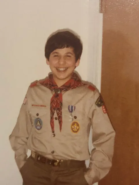 Un joven Adam Hamawy sonríe con su uniforme de los Boy Scouts