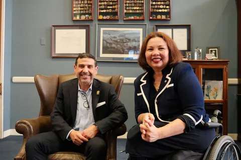 El Dr. Hamawy y la senadora Tammy Duckworth sonríen sentados uno junto al otro